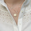 Reversible gold pendant necklace featuring Virgin Mary and M symbol, with ruby accents on back.