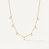 Golden plated silver necklace with square cubic zirconia dangle stones on a delicate chain, grey wood background.
