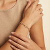 Adults wearing a golden plated silver clip bracelet featuring clear zirconia paved links on their wrist.