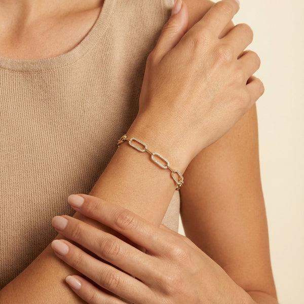 Adults wearing a golden plated silver clip bracelet featuring clear zirconia paved links on their wrist.